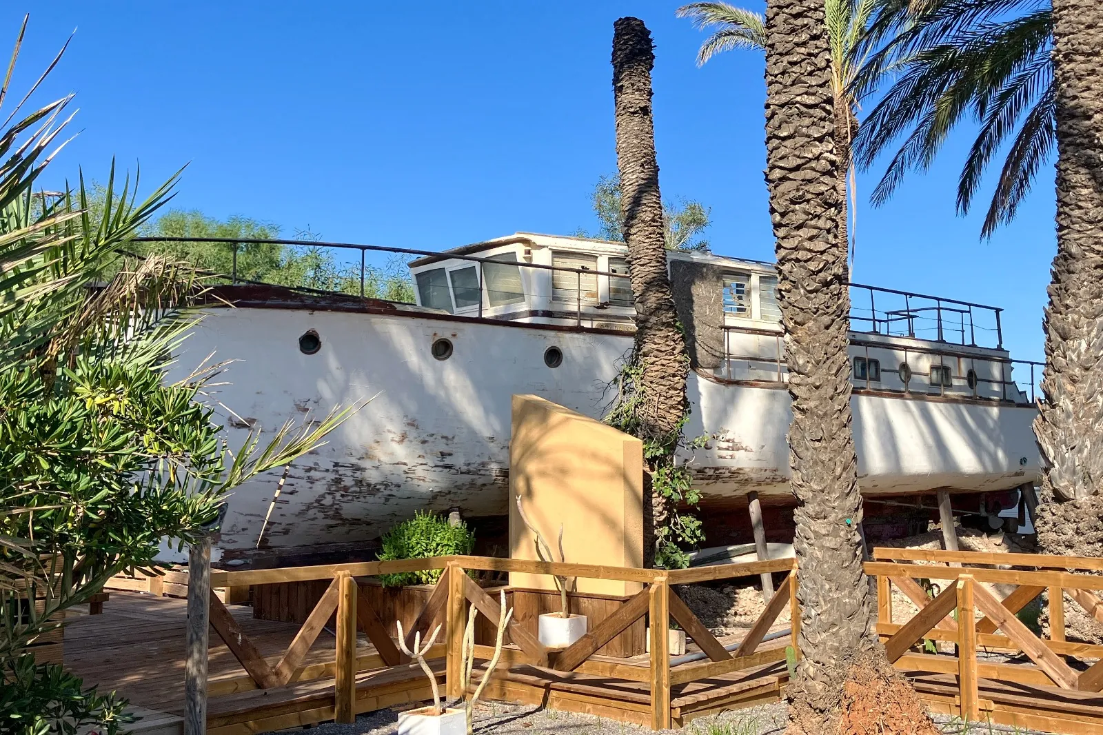 Barco varado entre palmeras en los jardines del camping