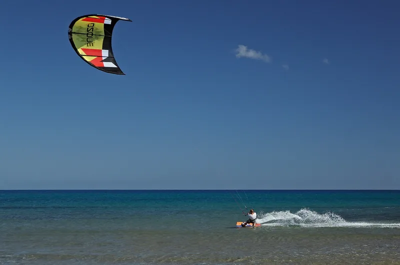 Kitesurfista navegando sobre aguas turquesas con su cometa en el cielo