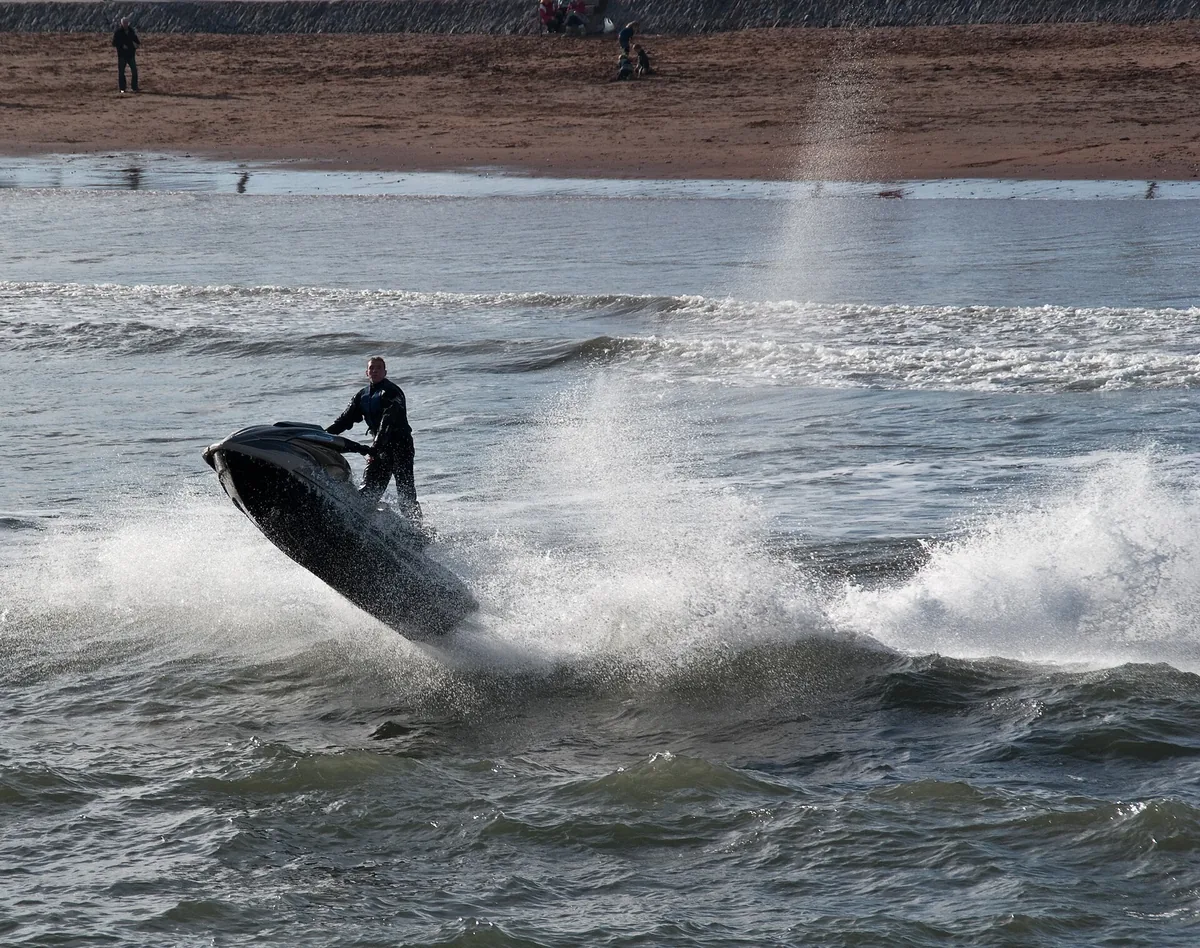 Moto de agua saltando sobre una ola levantando una cortina de spray