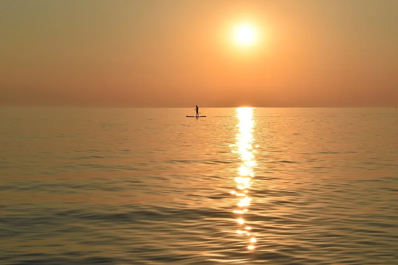 Paddle surfer remando en calma durante el atardecer